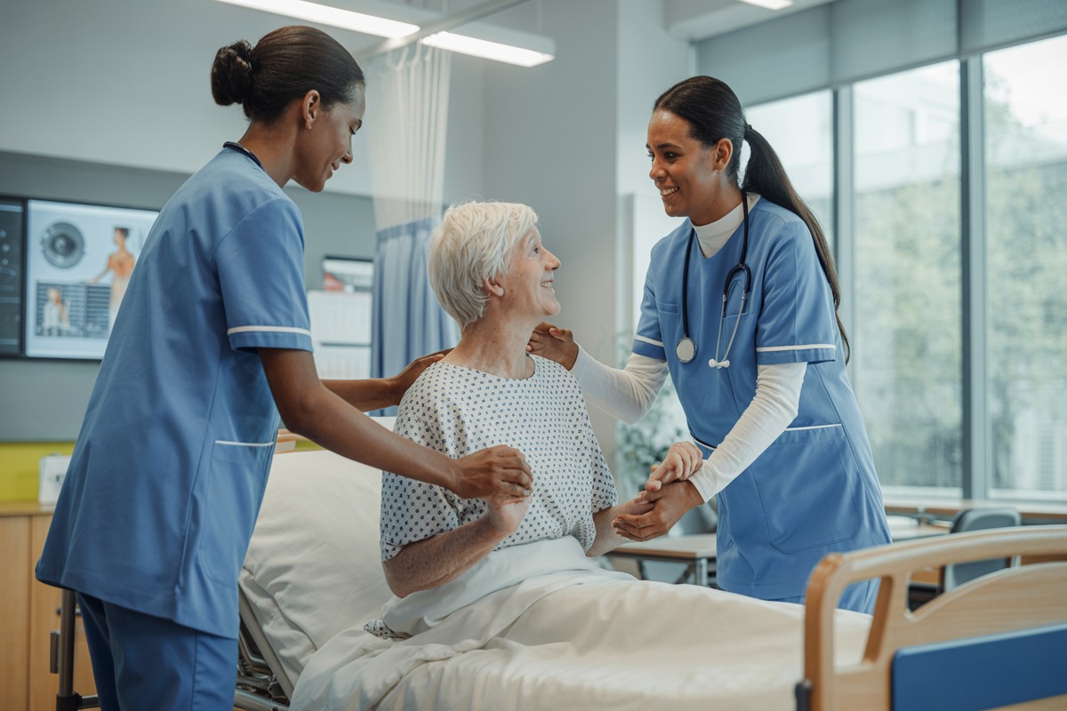 Tutor infirmier guide un étudiant lors d’un soin auprès d’un patient alité