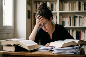 Une jeune candidate révisant avec concentration le concours de secrétaire de chancellerie dans son appartement.