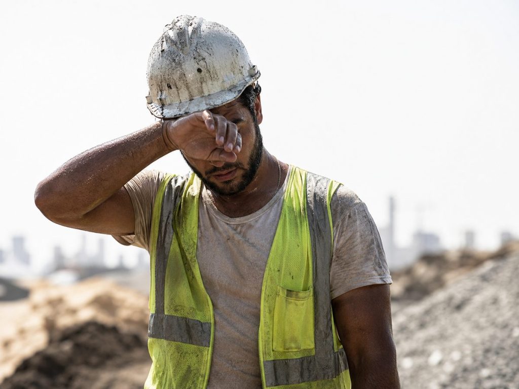 Ouvrier du bâtiment épuisé par la chaleur sur un chantier en plein soleil pendant la canicule