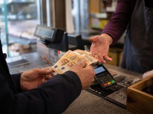 Client réglant un achat en espèces avec des billets de 50 euros à la caisse d'un commerce