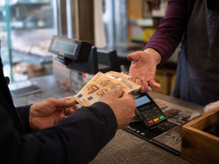 Client réglant un achat en espèces avec des billets de 50 euros à la caisse d'un commerce