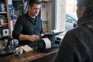 Commerçant encaissant un client sur une caisse enregistreuse tactile en boutique