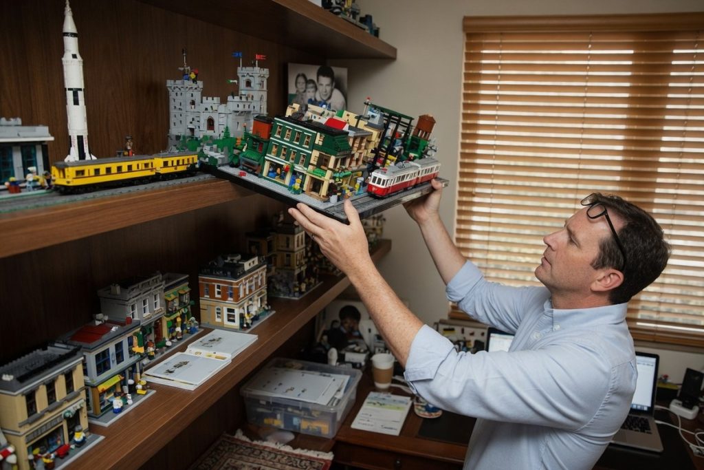 Collectionneur soulevant un modèle Lego dans une étude lumineuse