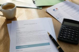 Documents fiscaux et contrat d'assurance-vie posés sur un bureau avec calculatrice, illustrant les placements qui conservent le PFU à 30% après la hausse de la CSG en 2026