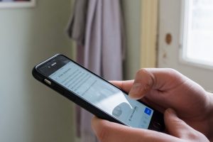 Mains tenant un smartphone dans un couloir domestique lumineux